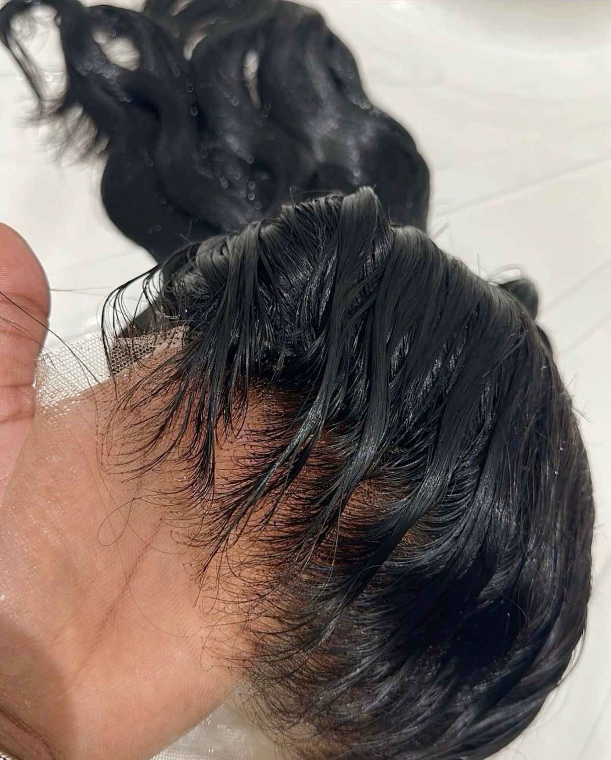 Black woman gently washing and conditioning her raw human hair wig
